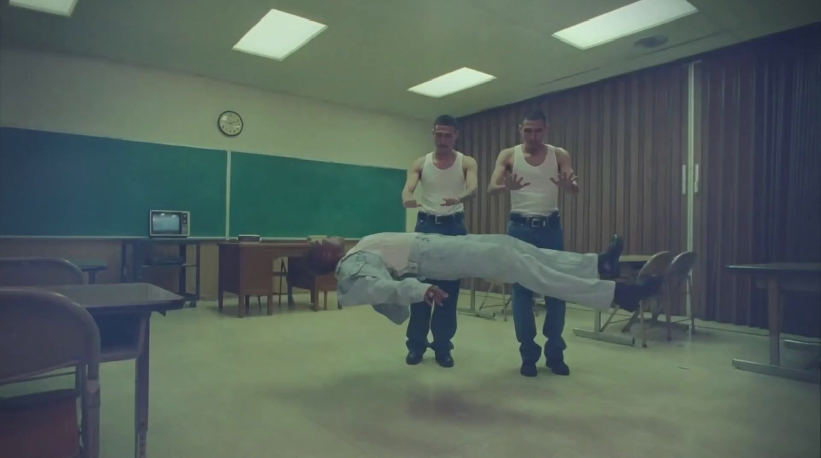 two men standing in a room with a person upside down on the floor