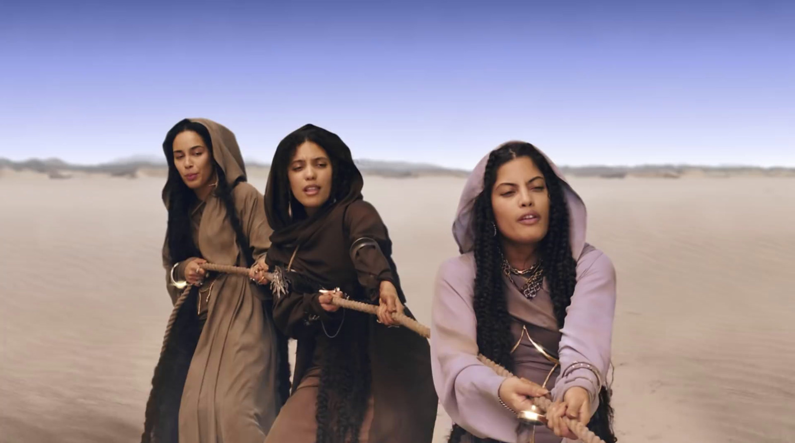 a group of three women walking across a desert