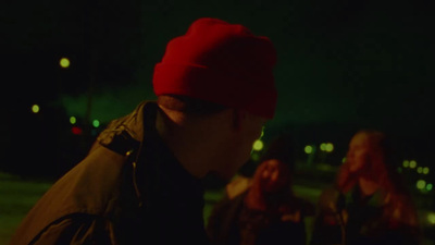 a man wearing a red beanie standing next to a woman