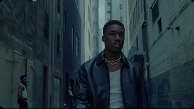 a man in a leather jacket walking down a street