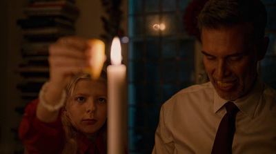 a man and a little girl standing in front of a candle