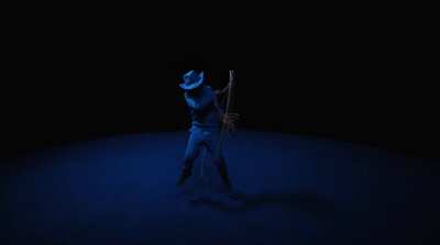 a man standing in the dark with a hat on