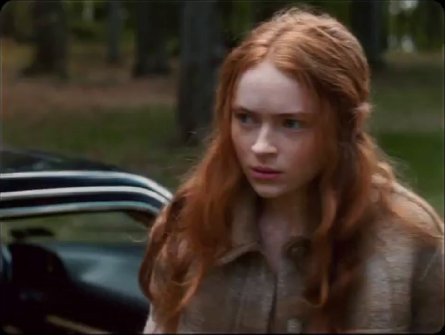 a woman with red hair standing next to a car