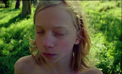 a young woman with her eyes closed sitting in the grass