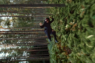 a man walking across a bridge made of trees