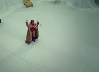 a woman in a red dress and coat sitting on a snow covered ground