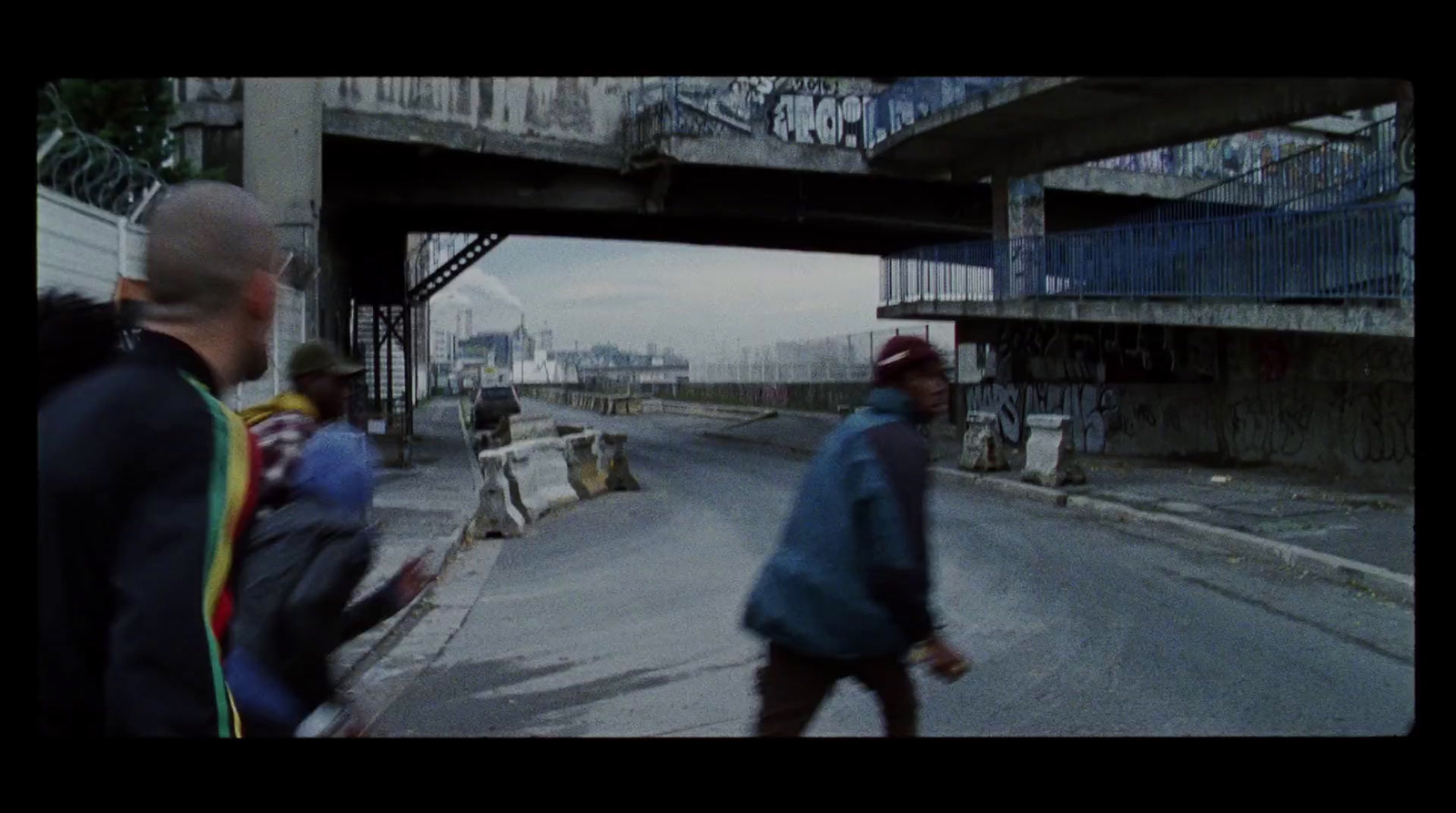 a group of people walking down a street under a bridge