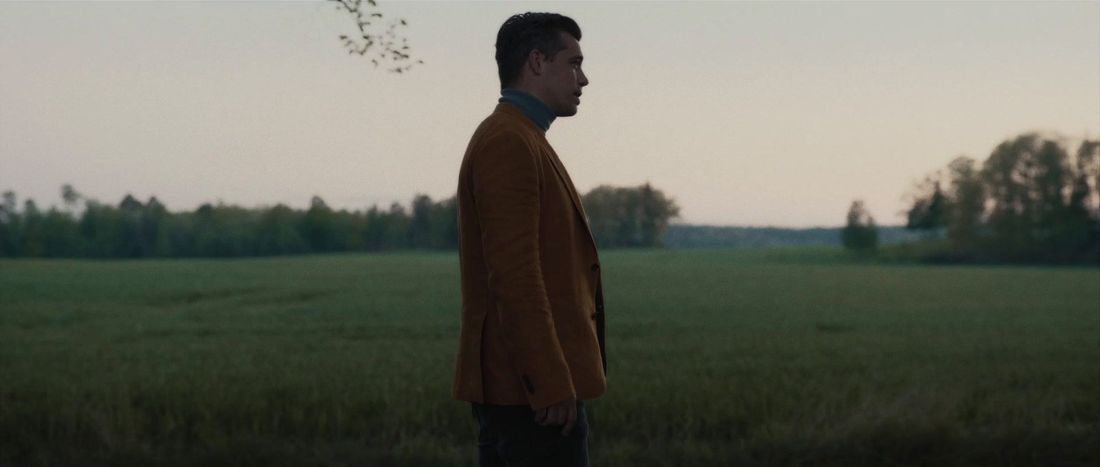 a man standing in a field with trees in the background