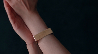 a woman's arm with a gold bracelet on it