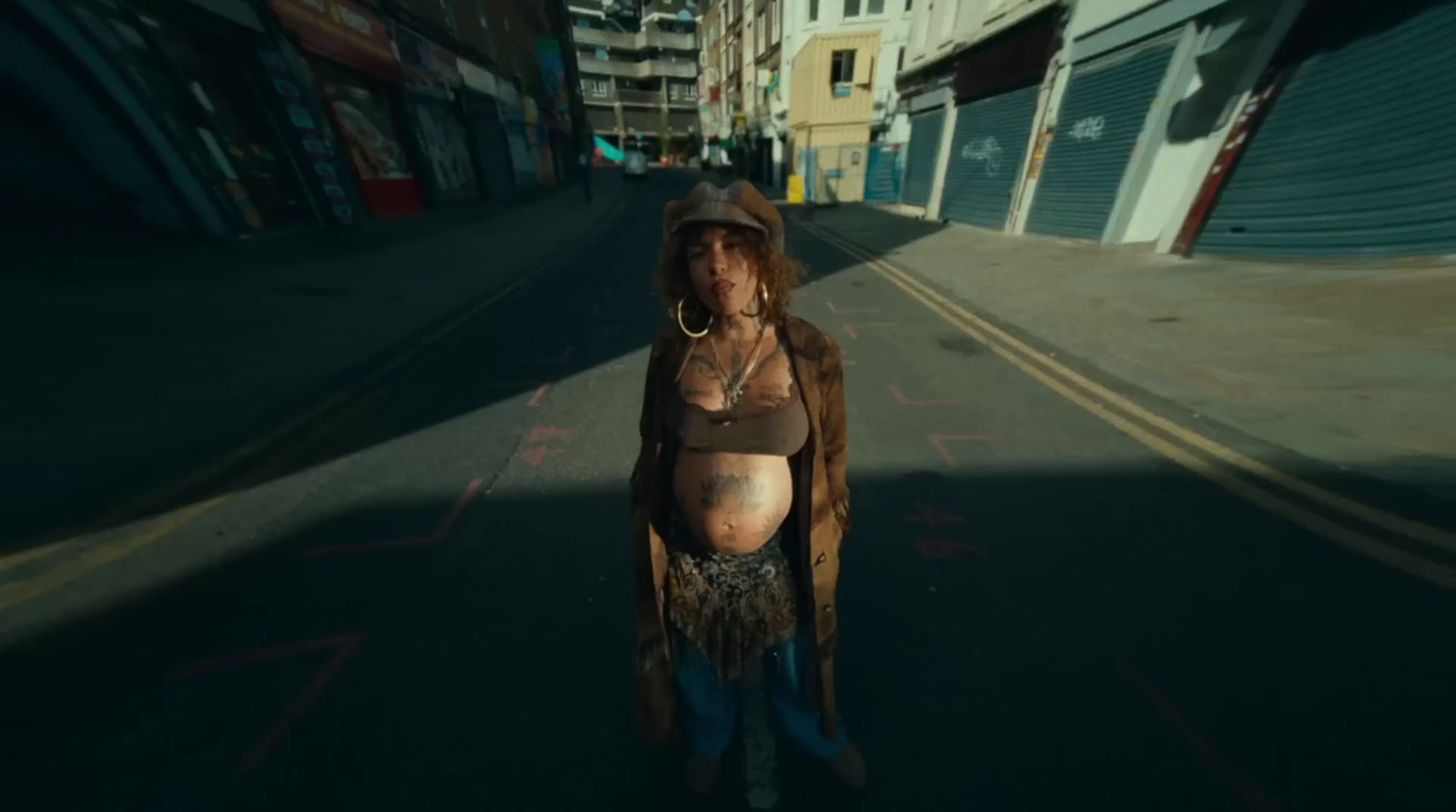 a pregnant woman standing in the middle of a street