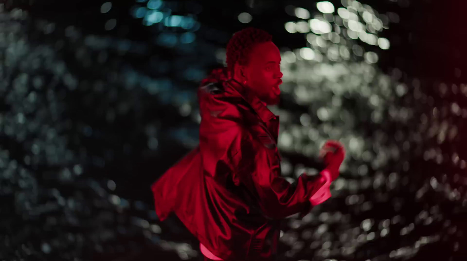 a man in a red jacket is running in the rain