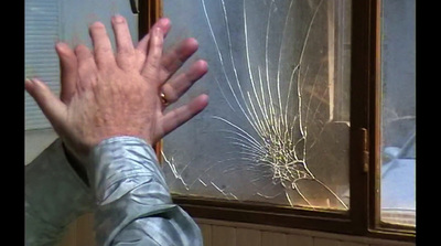 a man holding his hand up to a broken window