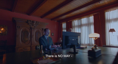 a man sitting at a desk in front of a tv