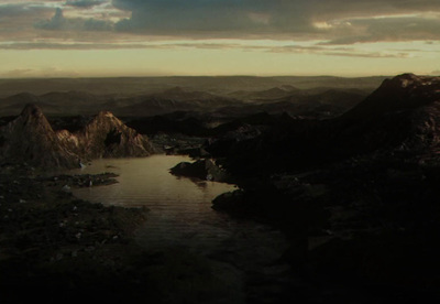 a body of water surrounded by mountains under a cloudy sky