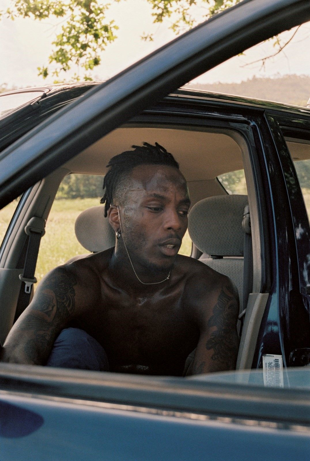 a man with tattoos sitting in a car