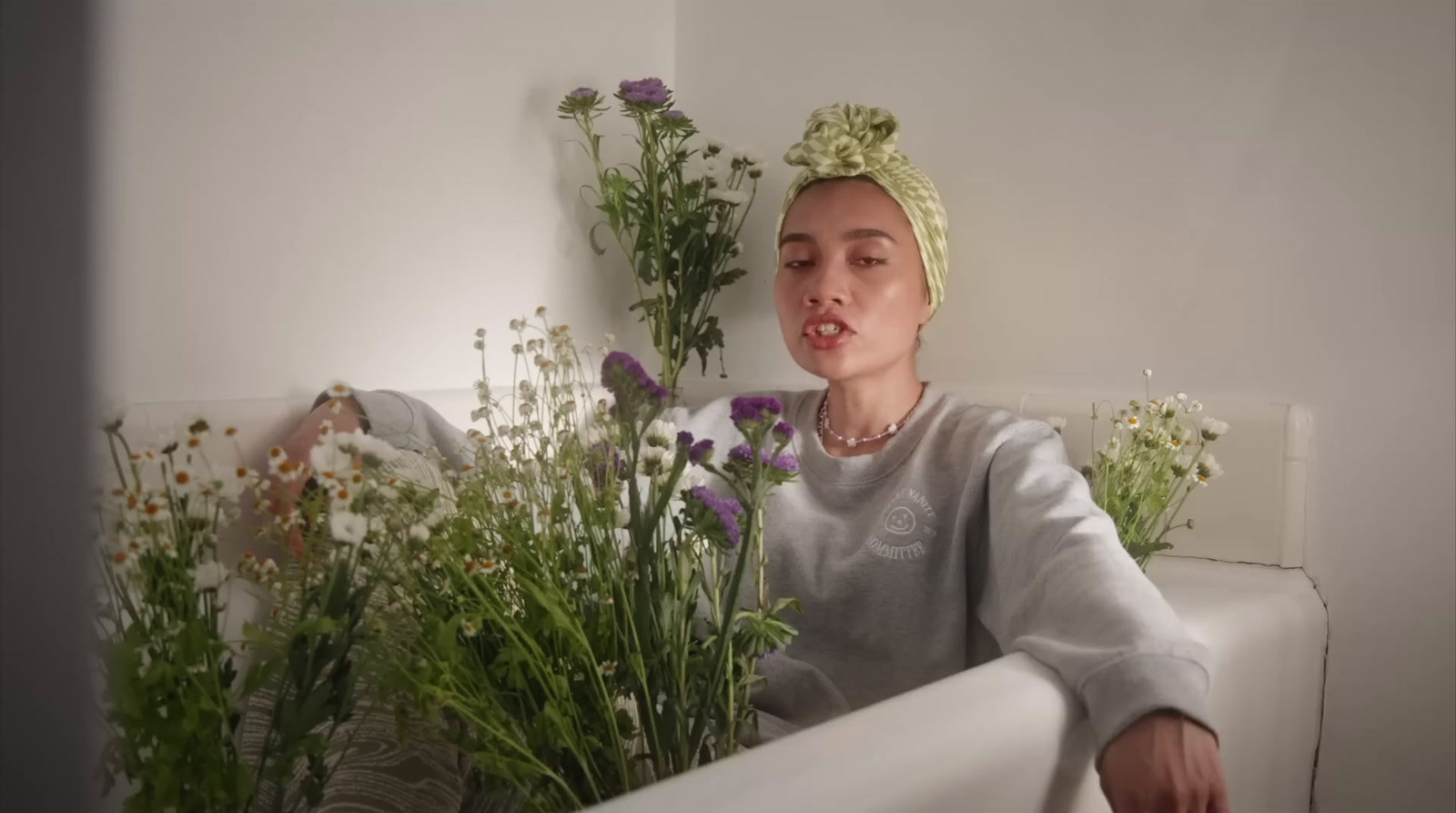 a woman sitting on a bathtub next to a bunch of flowers