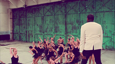 a man in a white jacket and a group of dancers