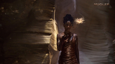 a woman in a brown dress standing in a cave