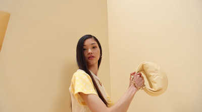 a woman in a yellow shirt is holding a hat