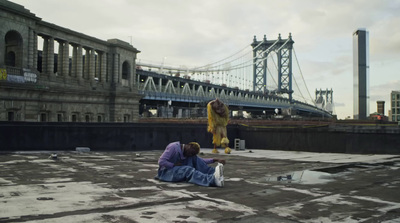 two people sitting on the ground in front of a bridge