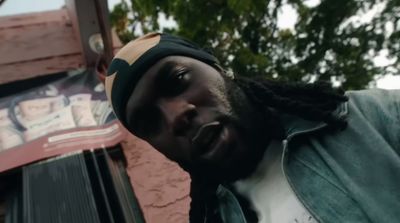 a man with dreadlocks standing in front of a building