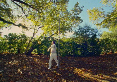 a man standing in the middle of a forest holding a baseball bat