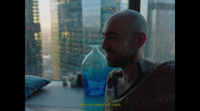 a man sitting in front of a window next to a blue bottle