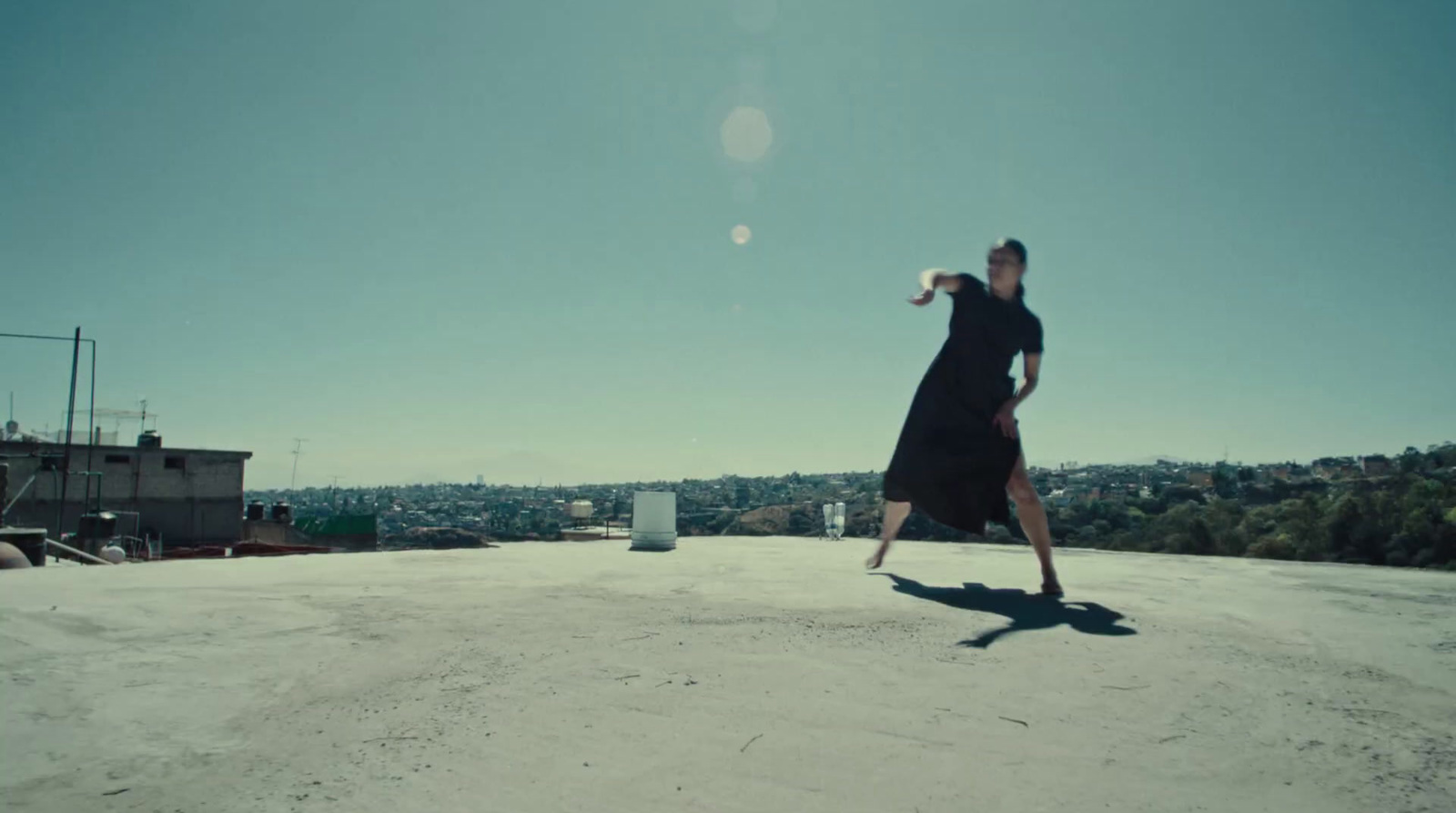 a woman in a black dress is throwing a frisbee