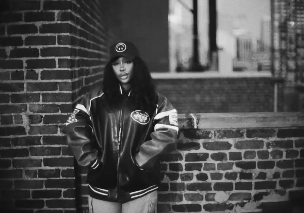 a black and white photo of a woman leaning against a brick wall