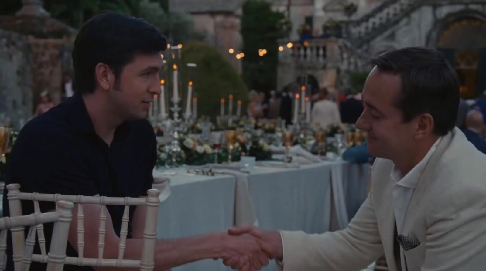 two men shaking hands at a dinner table