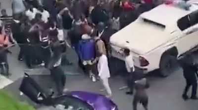 a crowd of people standing around a white van