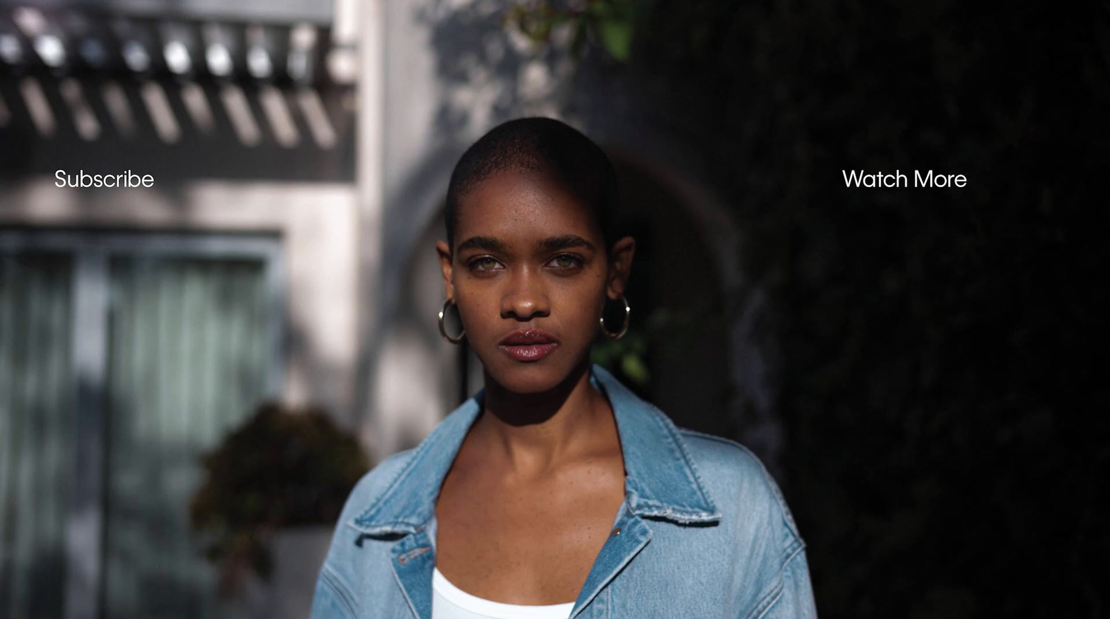 a woman wearing a denim jacket and earrings