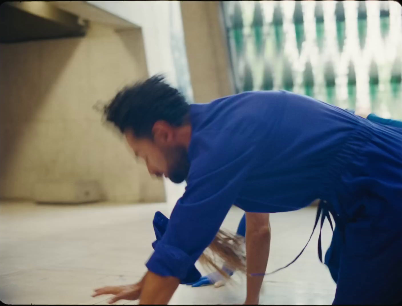 a man in a blue shirt bending over on a skateboard