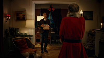 a man standing in a living room next to a christmas tree