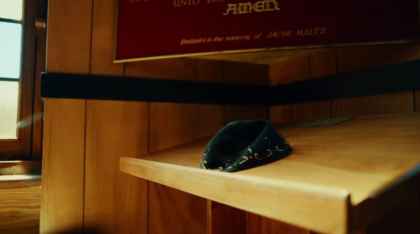 a hat sitting on a wooden shelf in front of a window