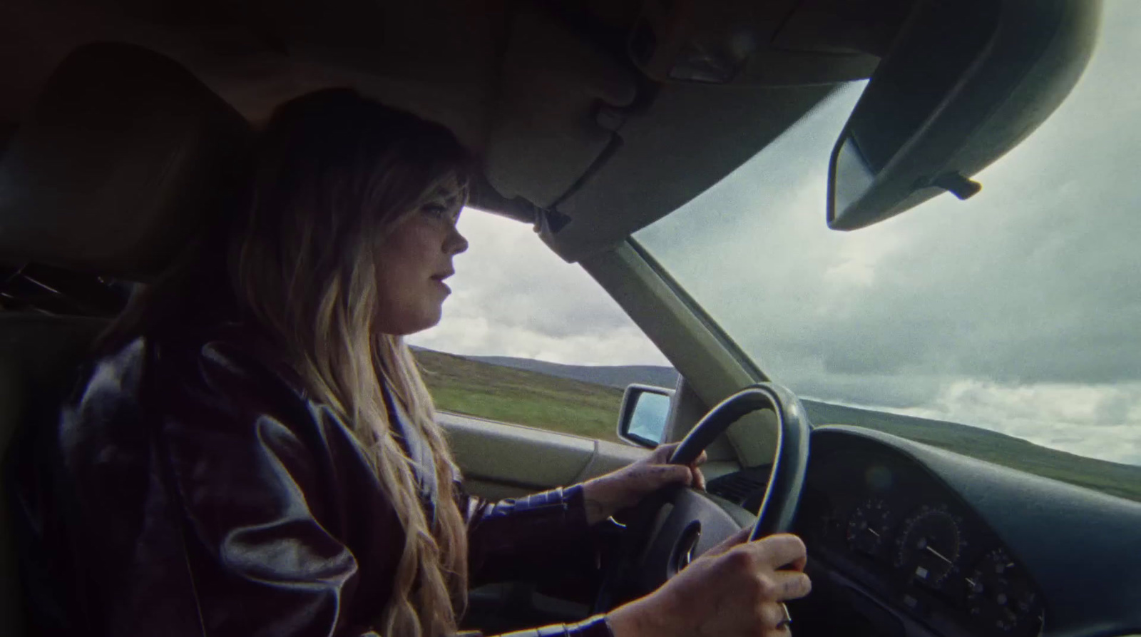 a woman driving a car on a cloudy day