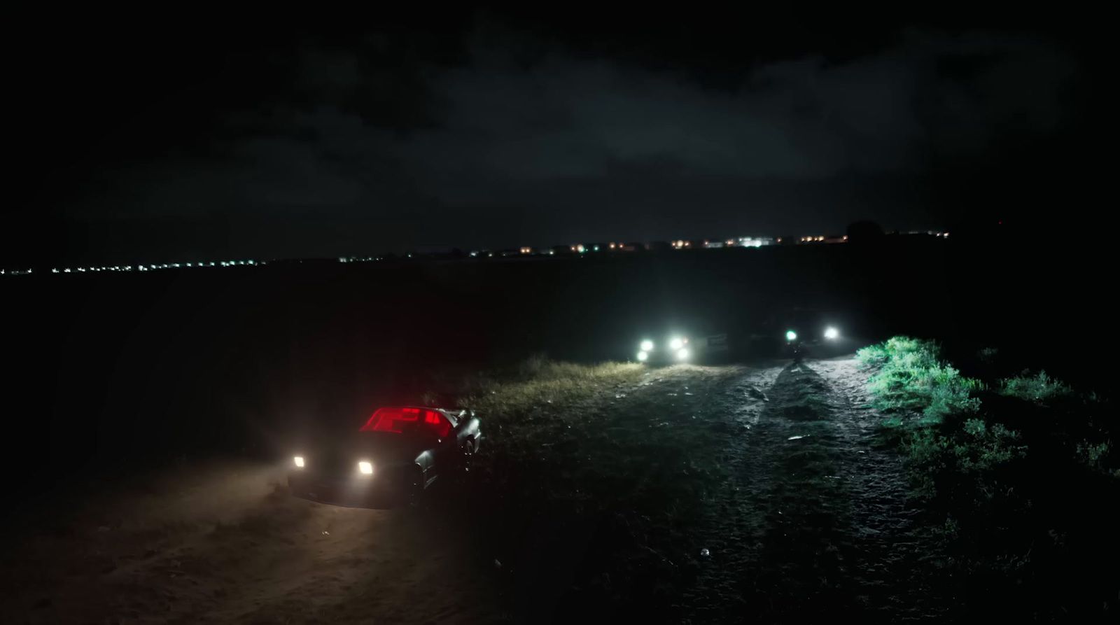 a car driving down a dirt road at night