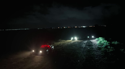 a car driving down a dirt road at night