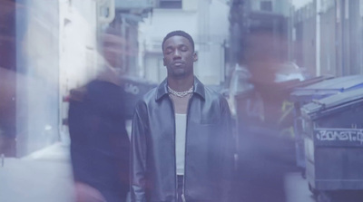 a man in a leather jacket standing in a street