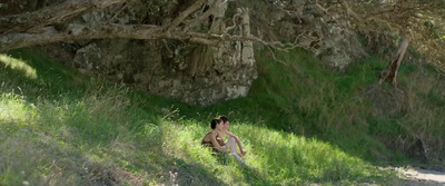 a woman sitting in the grass under a tree