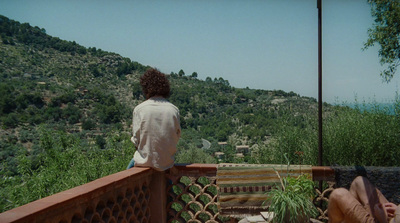 a person sitting on a balcony overlooking a valley