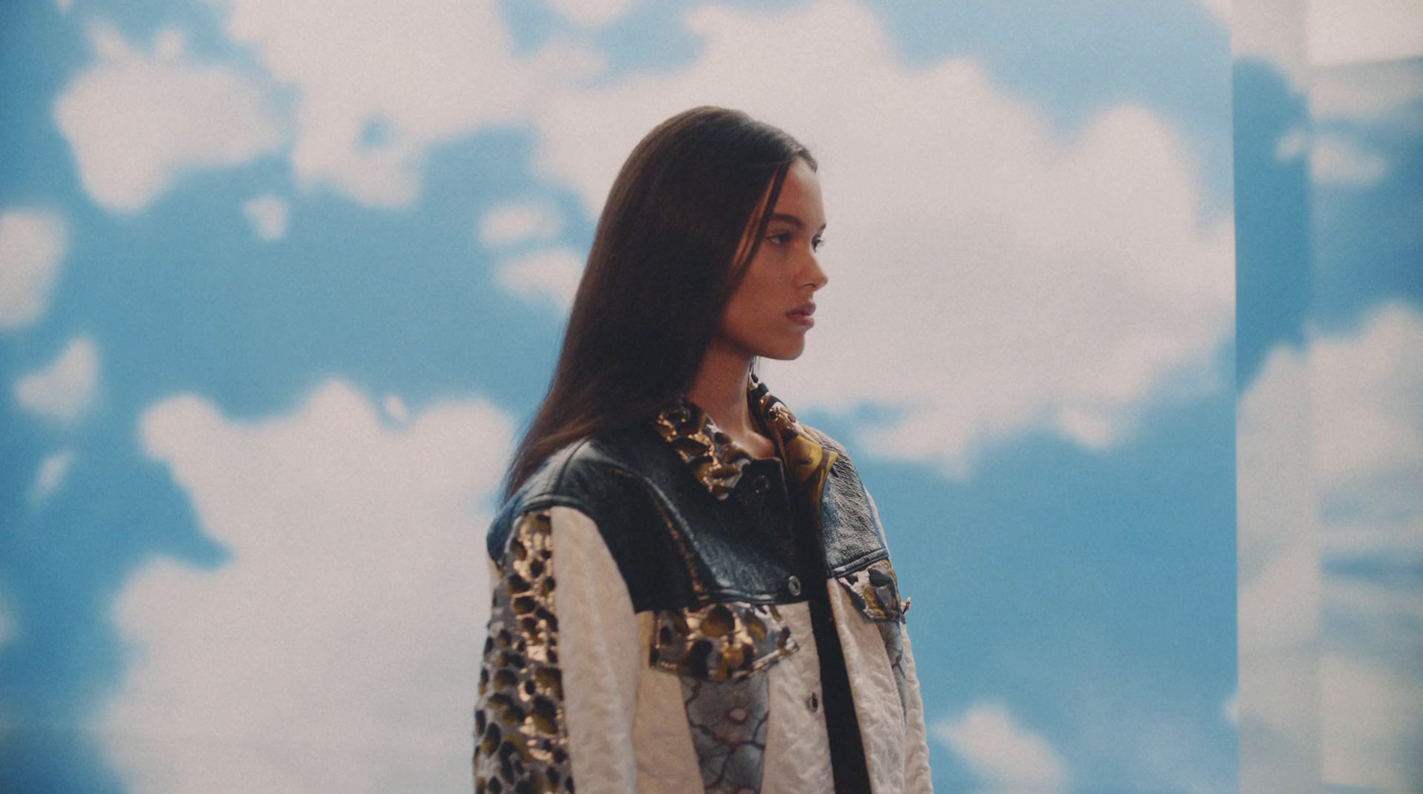 a woman standing in front of a blue sky with clouds