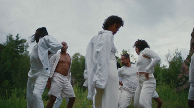 a group of people dressed in white walking through a field