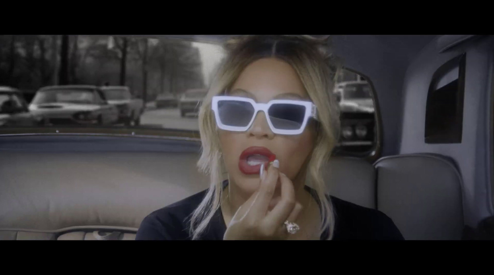 a woman in sunglasses smoking a cigarette in a car