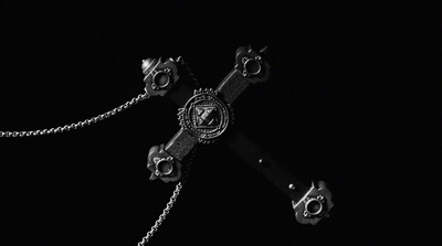 a black and white photo of a cross on a chain