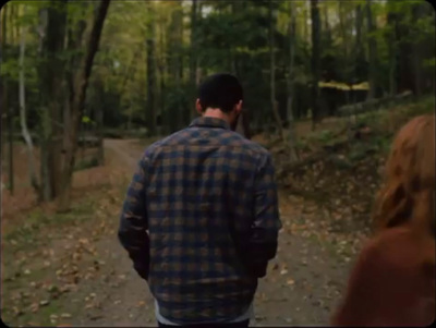 a man and a woman walking down a path in the woods