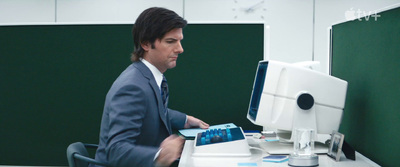 a man in a suit sitting in front of a computer