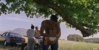 a man holding a baby under a tree