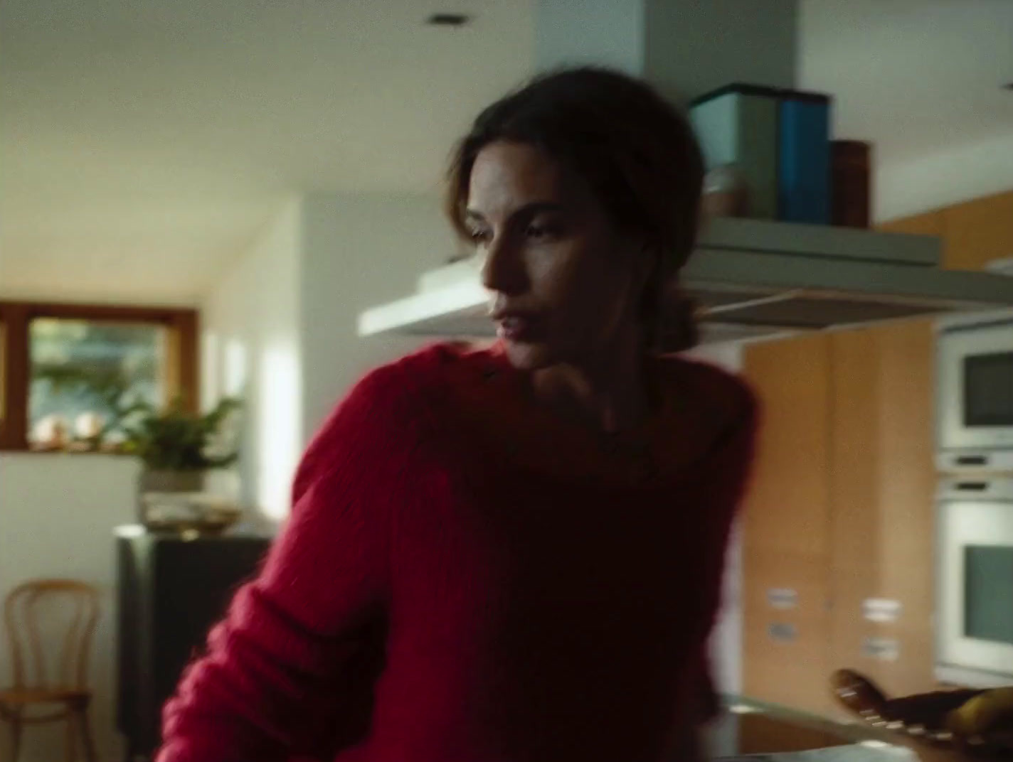 a woman in a red sweater standing in a kitchen