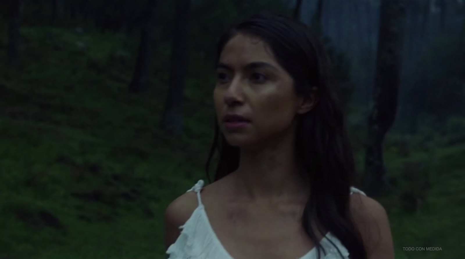 a woman in a white dress standing in a forest